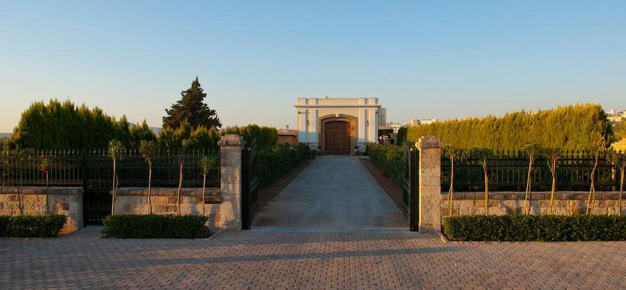 Gikas winery building seen from the front and the entrance has lawn green, fence and stone walkway